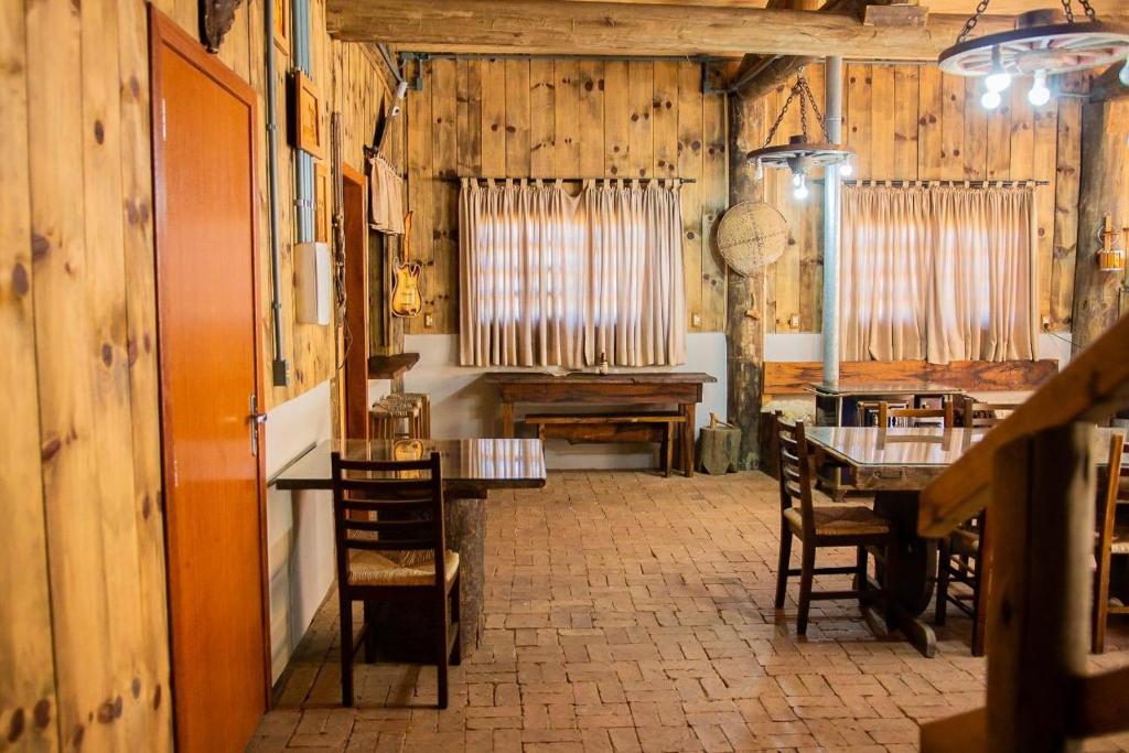 a dining room with wooden walls and tables and chairs at Hotel Queijo & Cia in Capão Alto