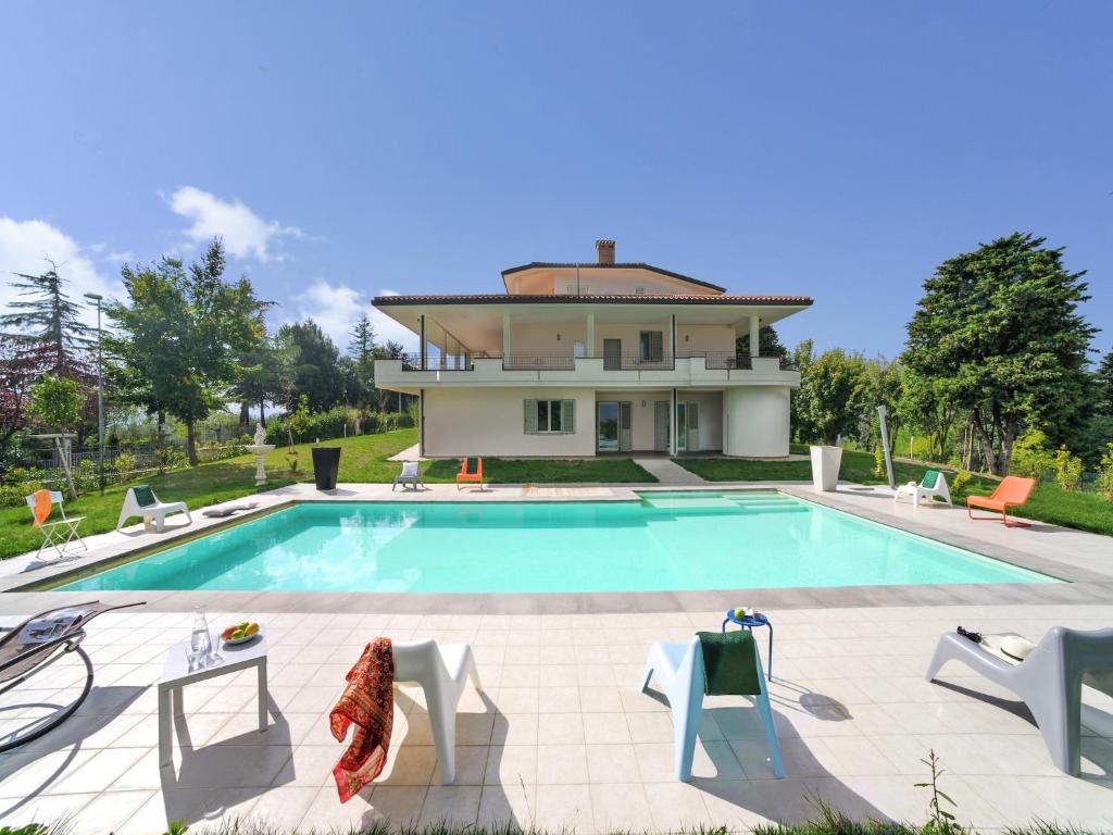 a villa with a swimming pool in front of a house at Tranquil Escape in Tavullia in Tavullia