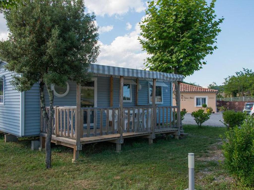 a blue tiny house with a large wooden deck at Mobil home confortable avec terrasse pour 6 personnes - API-1-52-393 in Saint-Maurice-dʼIbie