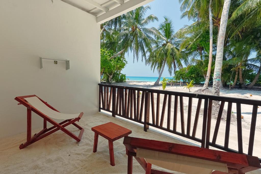 a balcony with a chair and a bench and the beach at Azul Retreat in Dhigurah