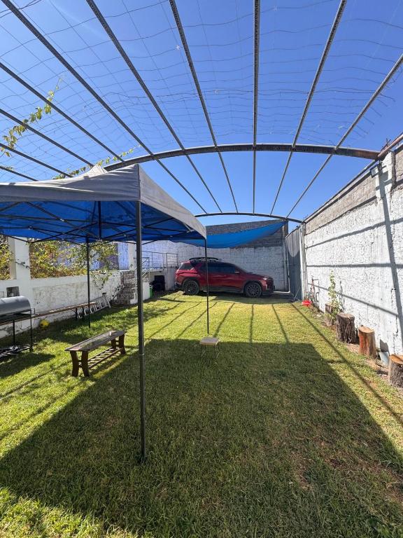 a canopy over a yard with a car parked under it at Casa Campo con piscina, billar, casa árbol, y huerta a 10 minutos de la FIA in Socabaya