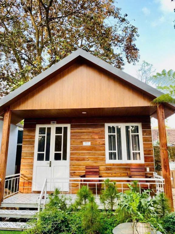 a small log cabin with a porch and a white door at Châu Homestay in Thôn Dương Xuân Hạ