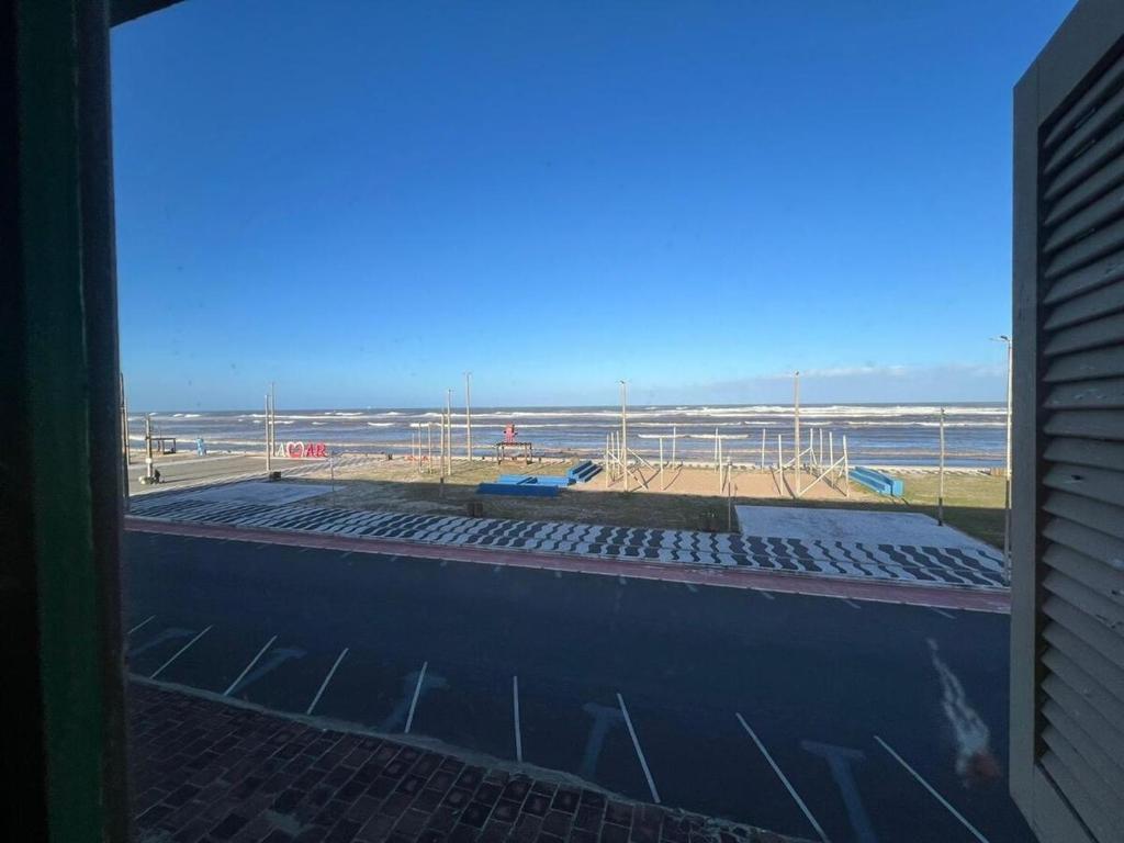 una ventana de un edificio con vistas a la playa en Apartamento Pé na Areia, en Tramandaí