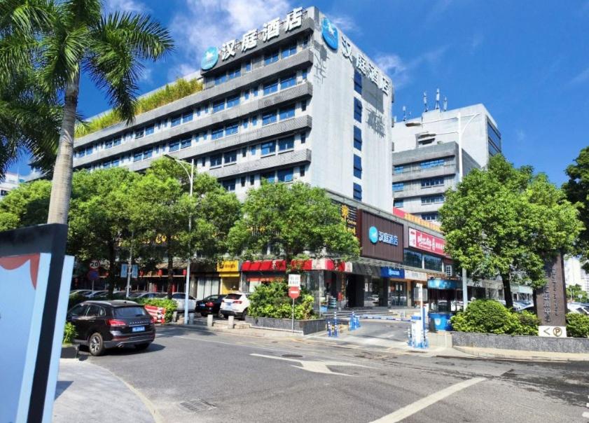a large building with cars parked in front of a street at Hanting Hotel Shenzhen Baoan Xixiang Taoyuan Subway Station in Shenzhen
