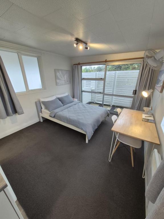 Un dormitorio con una cama y una mesa y ventanas. en Studio Parahaki, en Whangarei