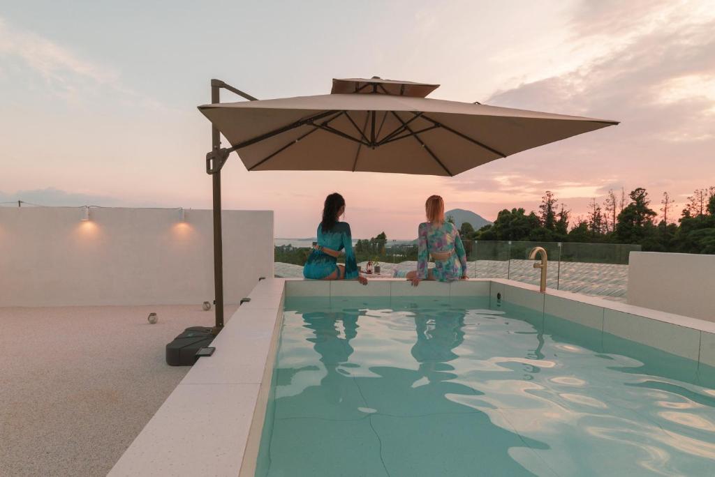 zwei Frauen unter einem Regenschirm neben einem Pool in der Unterkunft Casa Hoje in Seogwipo