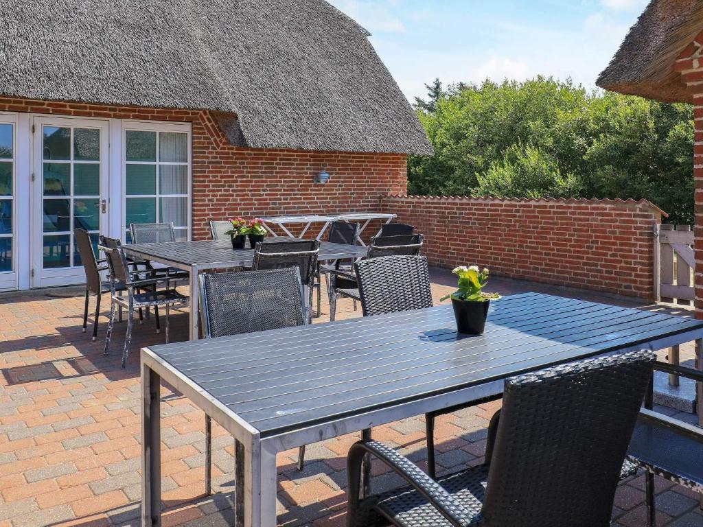 a patio with tables and chairs and a brick building at 18 person holiday home in Ulfborg-By Traum in Øby