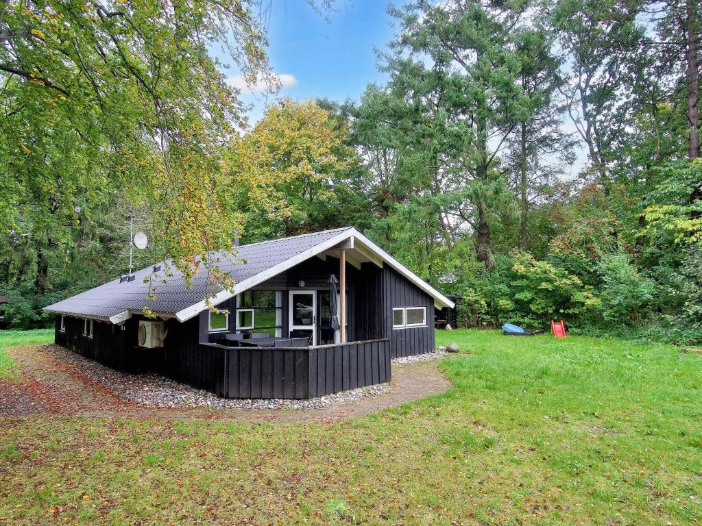 a small black house in a field with trees at 8 person holiday home in Melby-By Traum in Melby