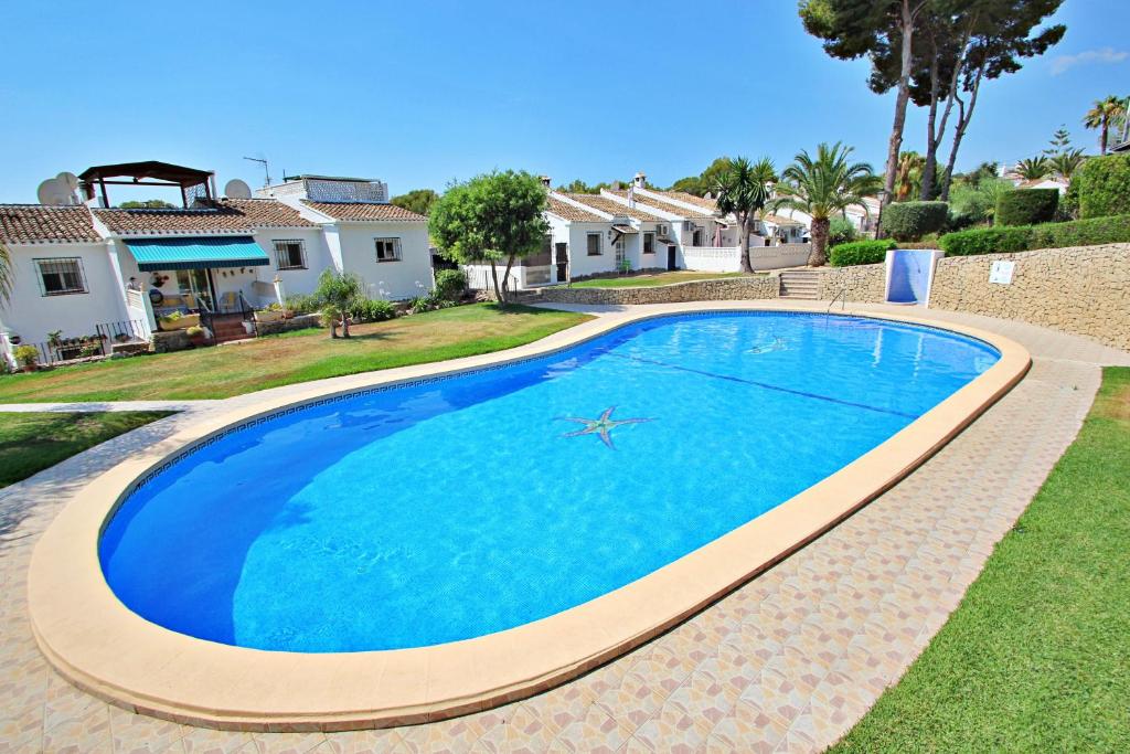 a large blue swimming pool in a yard with houses at Vista Mar - modern, well-equipped bungalow in Moraira in Teulada