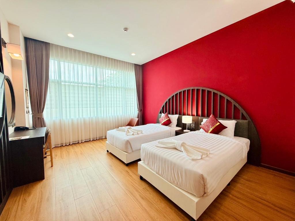 A twin room places two single beds beneath a bold red feature wall and curved headboard.