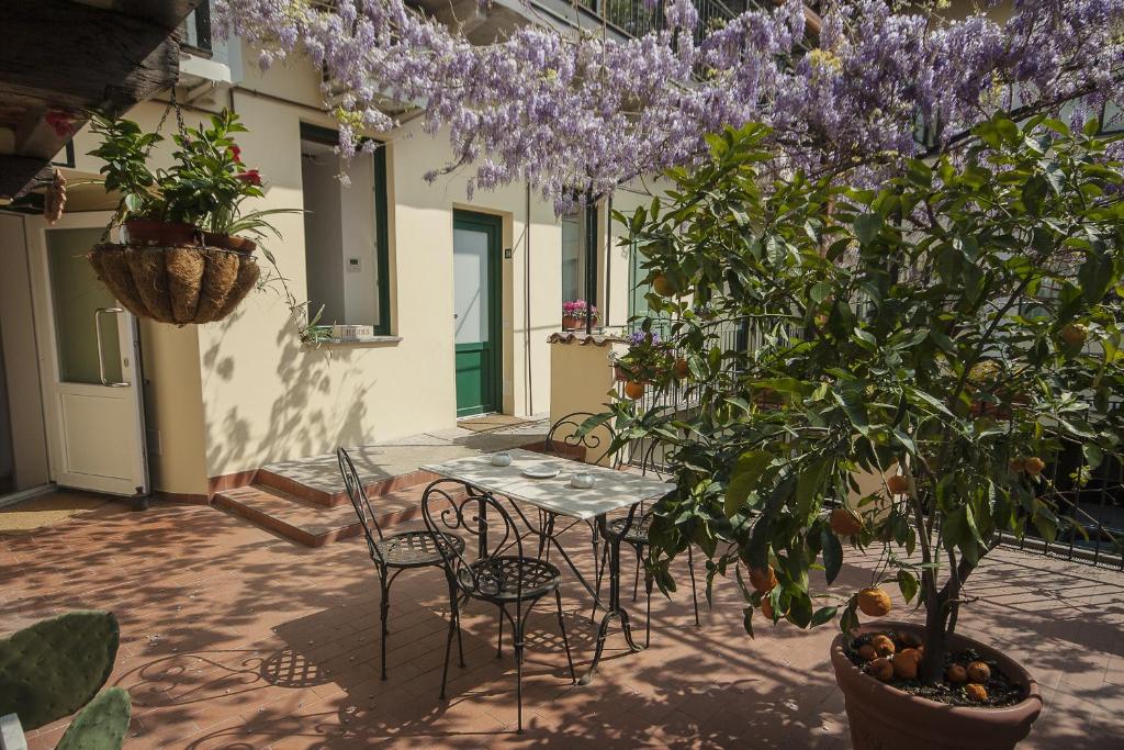 een patio met een tafel en stoelen en een boom met paarse bloemen bij Antica Corte in Busto Arsizio