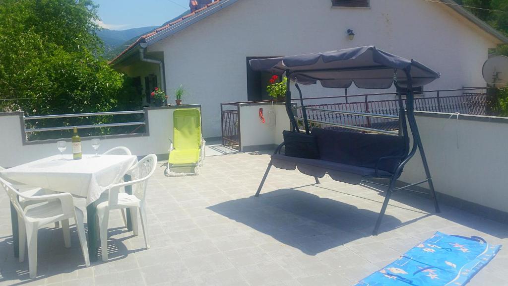 eine Terrasse mit einem Sonnenschirm, einem Tisch und Stühlen in der Unterkunft Apartmani Čempres Senj in Senj