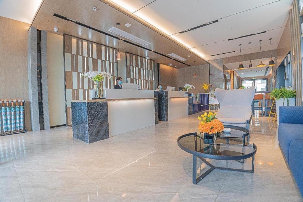 a lobby with a waiting area with a table and chairs at Echarm Hotel Zigong Machishui Wanda Plaza in Zigong