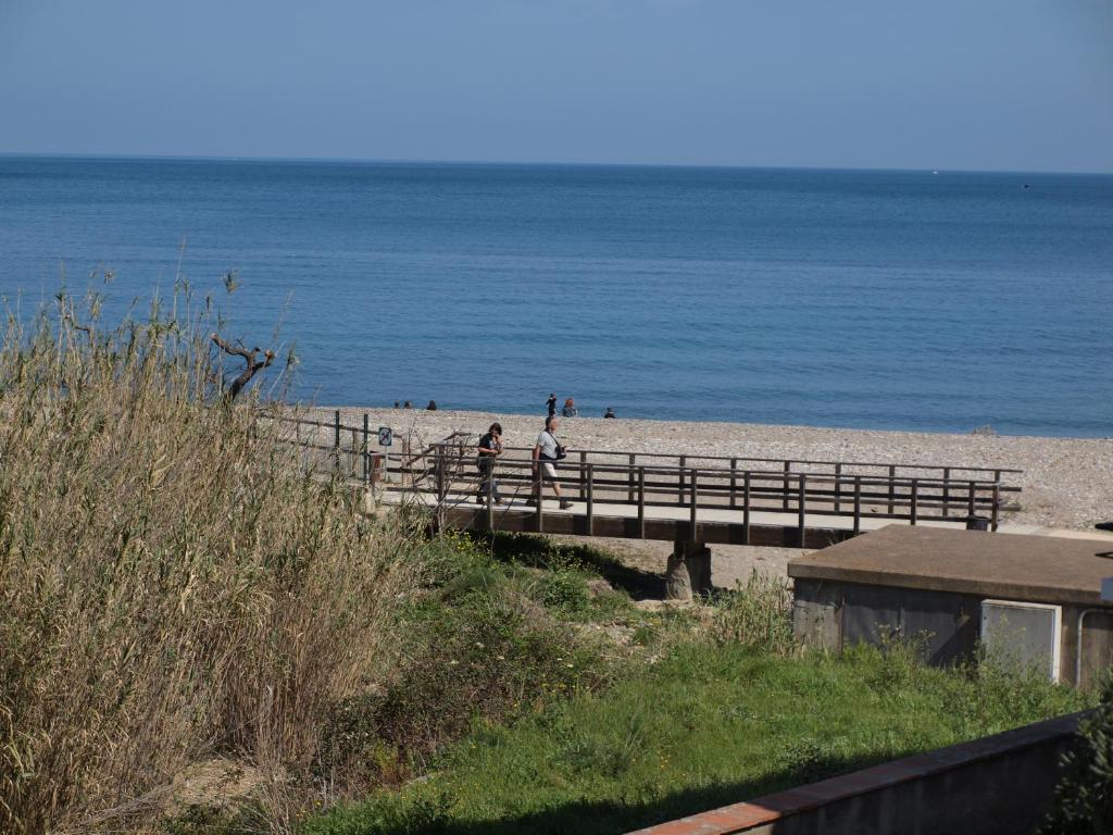 a beach with people walking on a wooden bridge at Cau de Creus in Port de la Selva