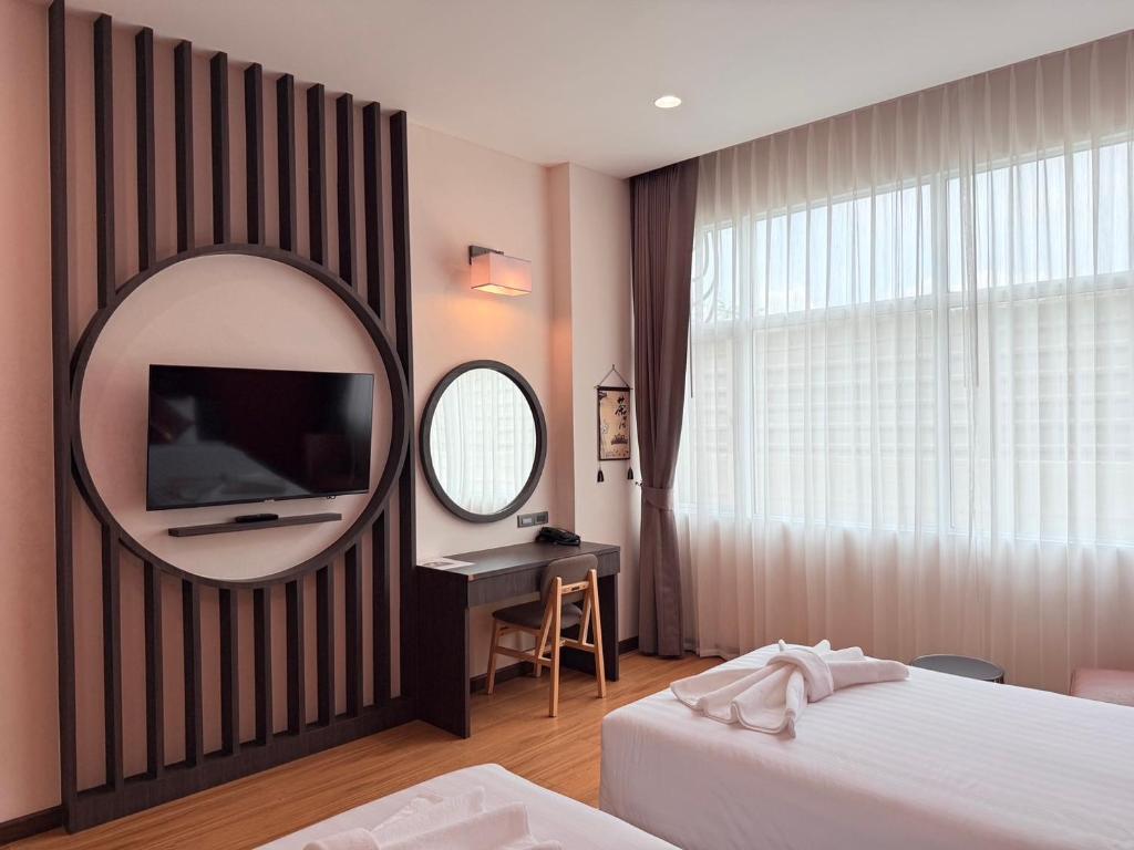 A softly lit bedroom with a decorative television wall, vanity and wide curtained window.