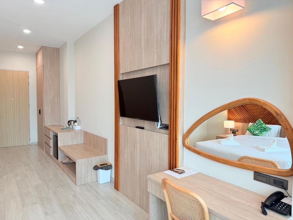 A bright room with a bed, built-in television and compact desk.