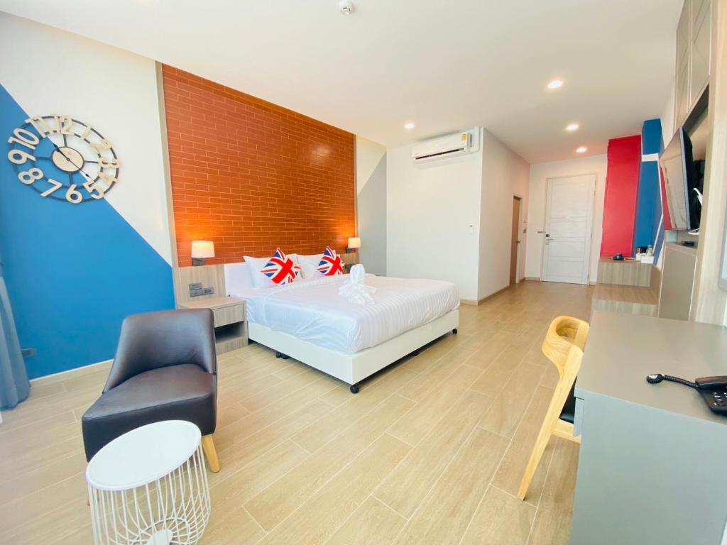 A colourful bedroom with a double bed, lounge chair and separate desk seating.
