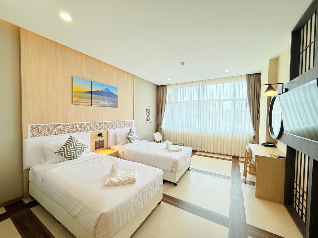 A spacious twin room with two beds, a large curtained window and a dressing desk.