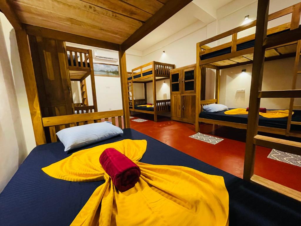 a room with two bunk beds with yellow sheets at Sigiri Serenity Hostel in Sigiriya