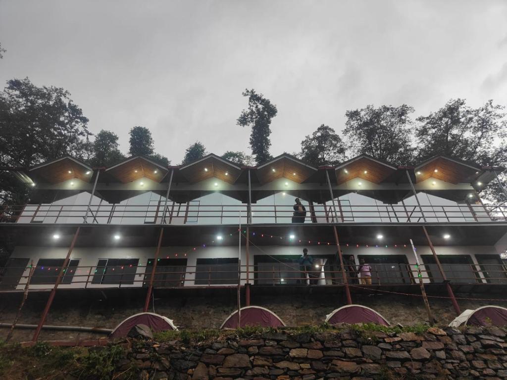 - un bâtiment avec des personnes sur le balcon la nuit dans l'établissement kedar hill resort, à Sonprayag