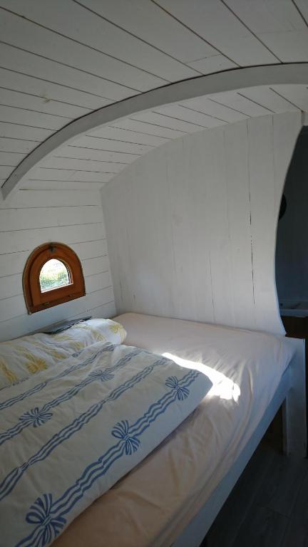 ein Bett in einem weißen Zimmer mit einem Fenster in der Unterkunft La Salicorne hébergement insolite in Saint-Germain-sur-Ay