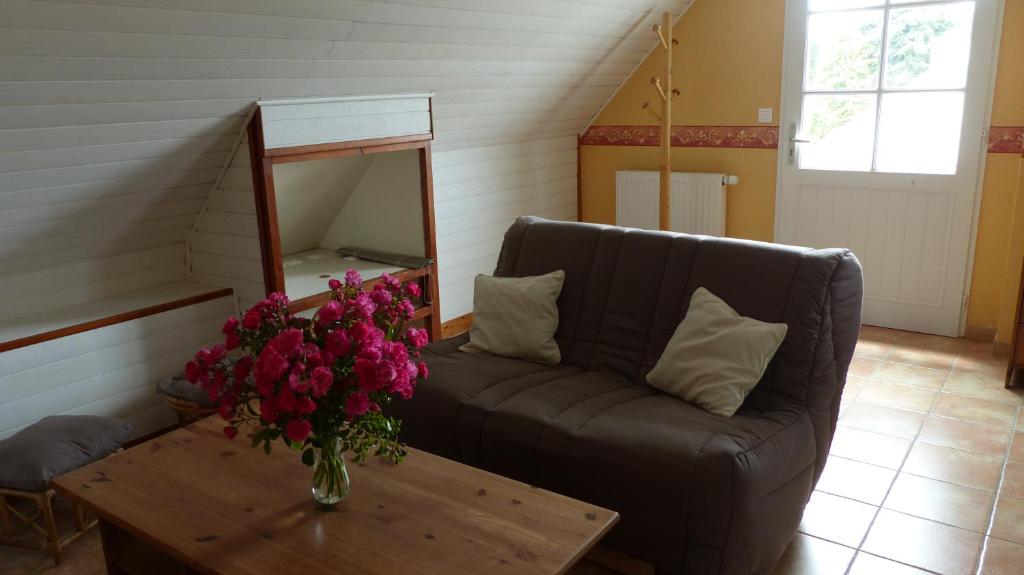 a living room with a couch and a vase of flowers on a table at Location 44410 in Saint-Lyphard