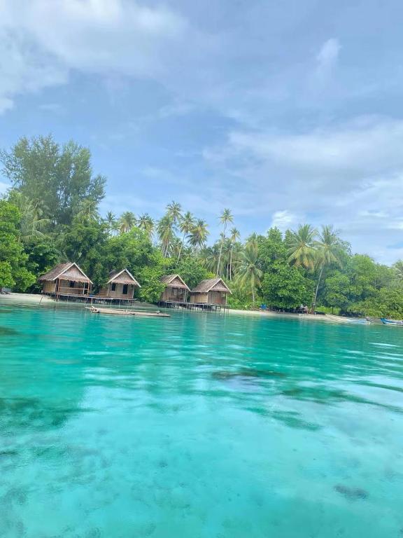 a group of overwater bungalows on an island in the ocean at Merpati homestay in Merpati