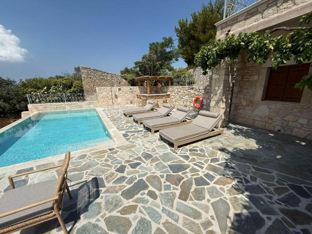 a pool with lounge chairs next to a house at Villa Iremia 