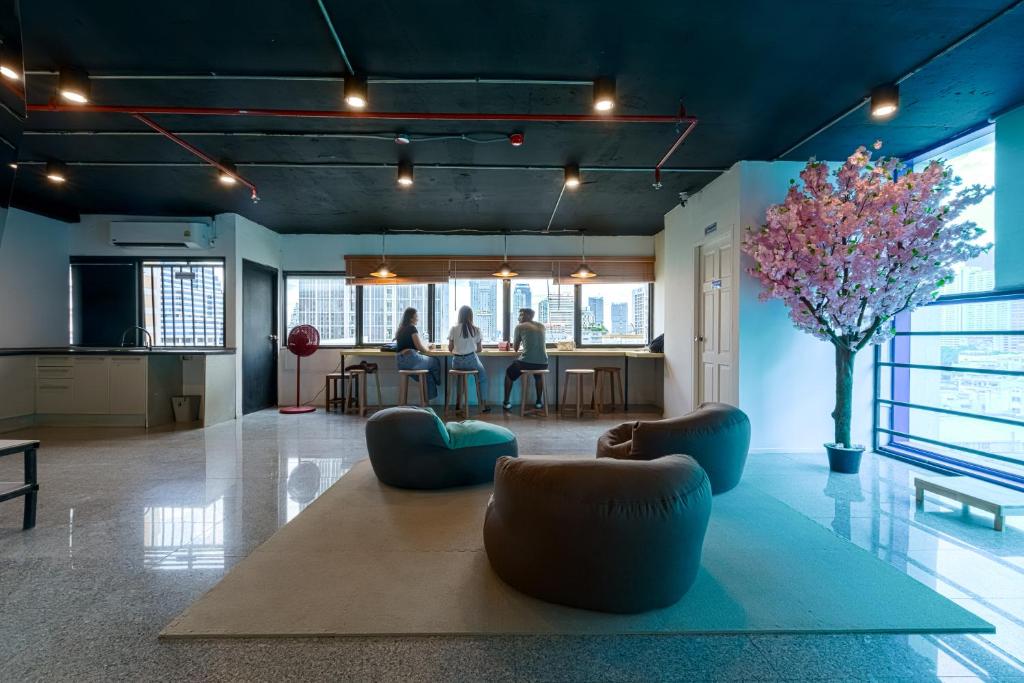 a living room with two people in the background at Kinboshi Silom in Bangkok