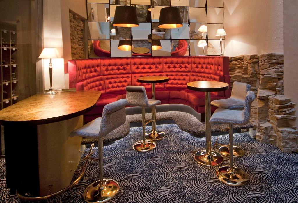 a lobby with a red couch and tables and chairs at Hotel Le Place d'Armes - Relais & Châteaux in Luxembourg