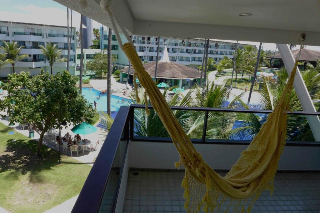 a balcony with a hammock and a swimming pool at Flat Ancorar 2201 in Porto De Galinhas