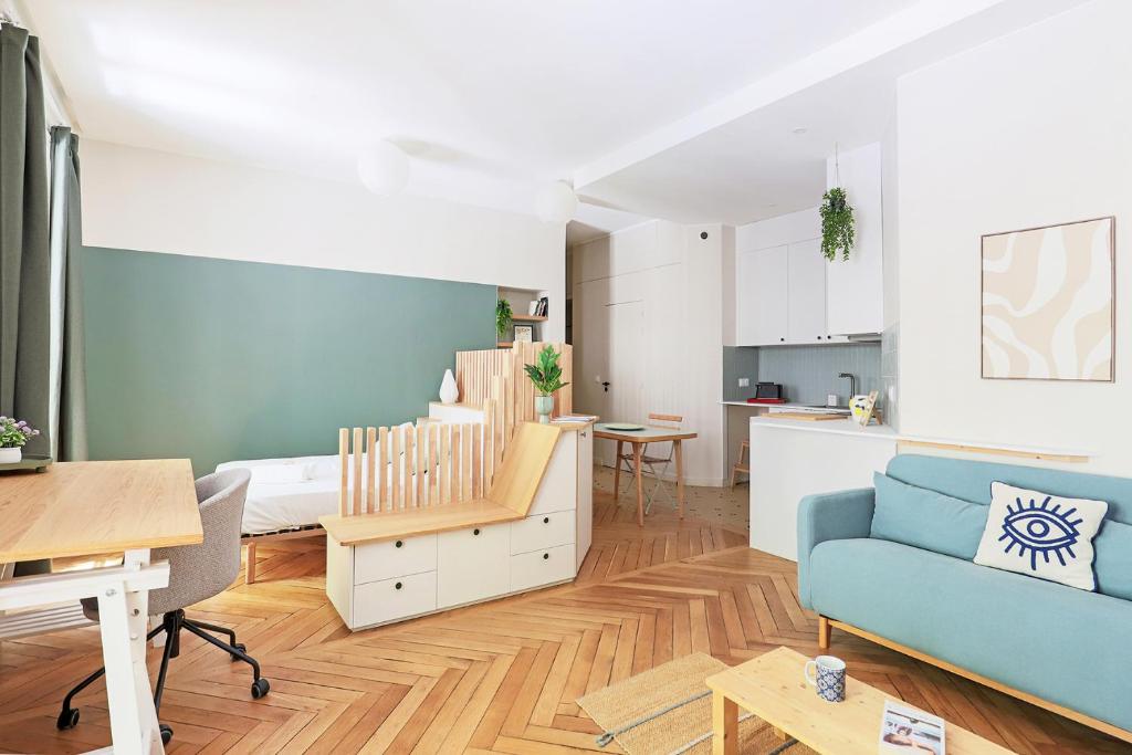 Una sala de estar con un sofá azul y una cocina. en Studio cosy et pratique, proche métro, par de la tête d'or, en Lyon