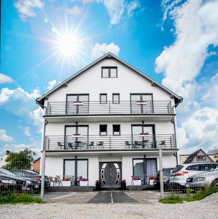 a white house with cars parked in front of it at Apartamenty Olivia in Władysławowo