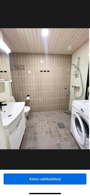a bathroom with a shower and a sink and a washing machine at Studio Lintulammentie in Oulu