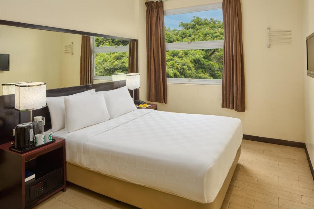 a bedroom with a large white bed and a window at Go Hotels Puerto Princesa in Puerto Princesa City
