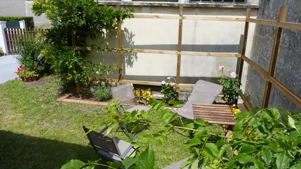 un jardin avec deux chaises et un banc en gazon dans l'établissement Apartment Le Jardinet, à Talence