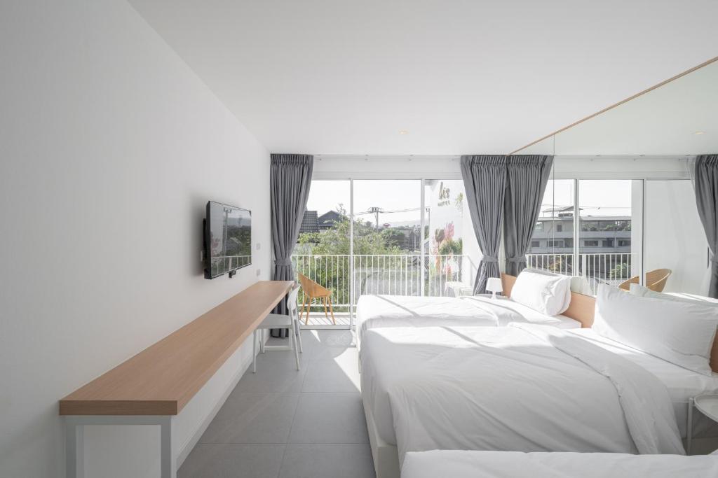 A bright twin room with a private-looking balcony, outdoor chairs and a long work surface.