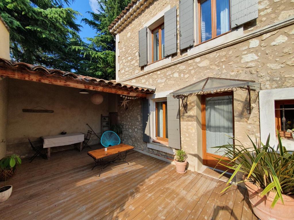 een patio van een huis met een houten terras bij Le nid douillet in Pertuis