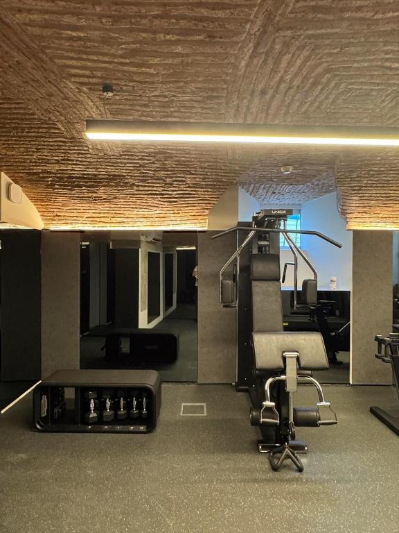 A compact gym occupies a low-ceilinged exposed-brick room with cardio and strength equipment.