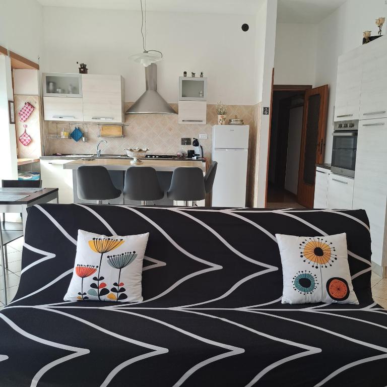 a living room with a couch with pillows and a kitchen at La Casa di Ale 2 - ampio e luminoso appartamento ai Castelli Romani in Marino