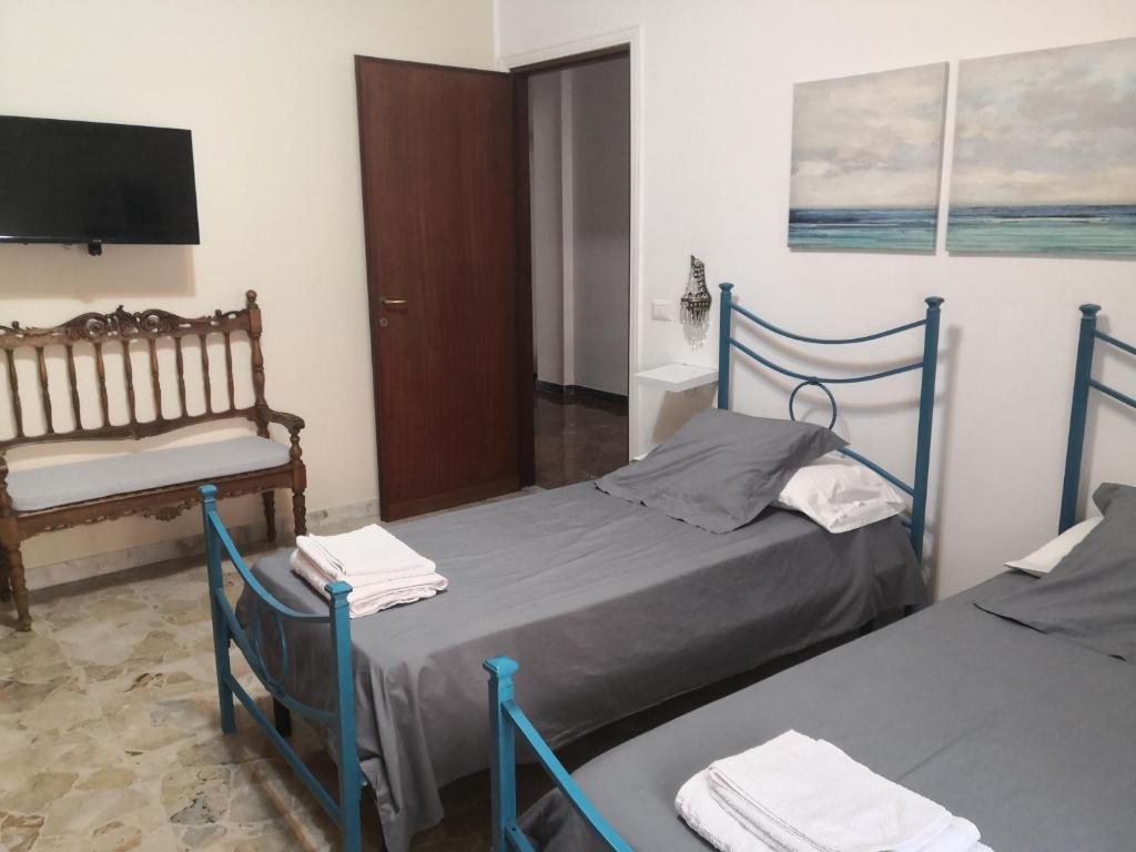 a room with two beds and a chair and a tv at CASA PAOLINA NEL CENTRO DI BRACCIANO in Bracciano