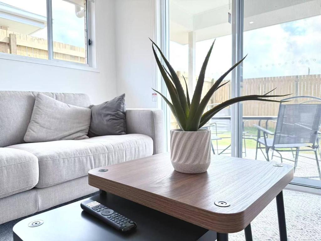 a living room with a couch and a table with a plant at Home Blanc - Brand New, Peaceful & Well Equipped in Ripley