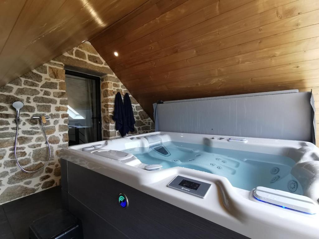 y baño con bañera y pared de piedra. en Au fil de l'eau, en Elliant
