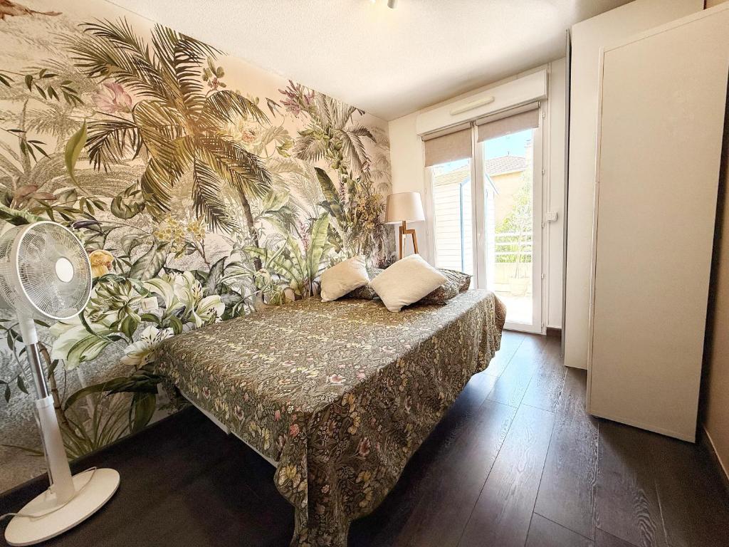 een slaapkamer met een bed met tropisch behang bij Apt with 2 bedrooms, terrace, pool & parking in Antibes