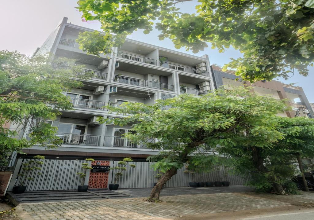 a tall white building with a tree in front of it at One Stayz by Zipcode in Gurgaon