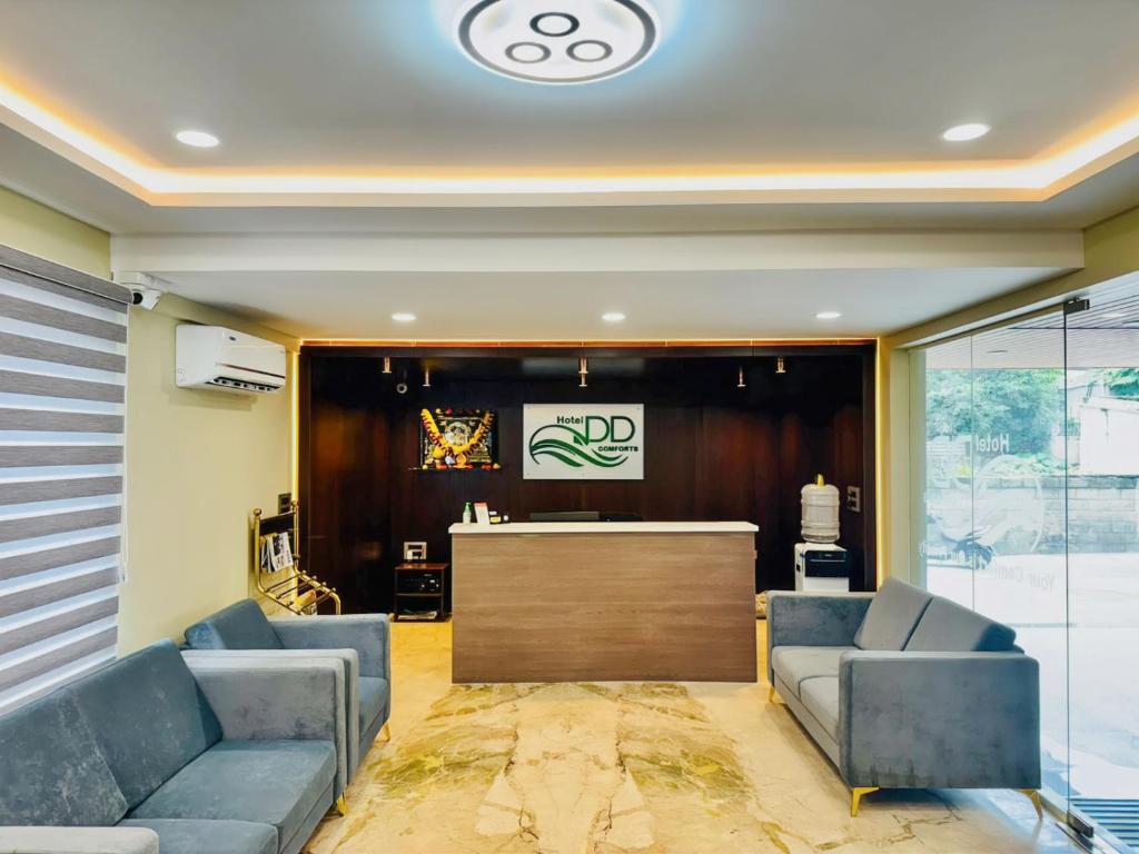 un vestíbulo con dos sofás azules y un bar en Hotel DD Comfort, en Bangalore