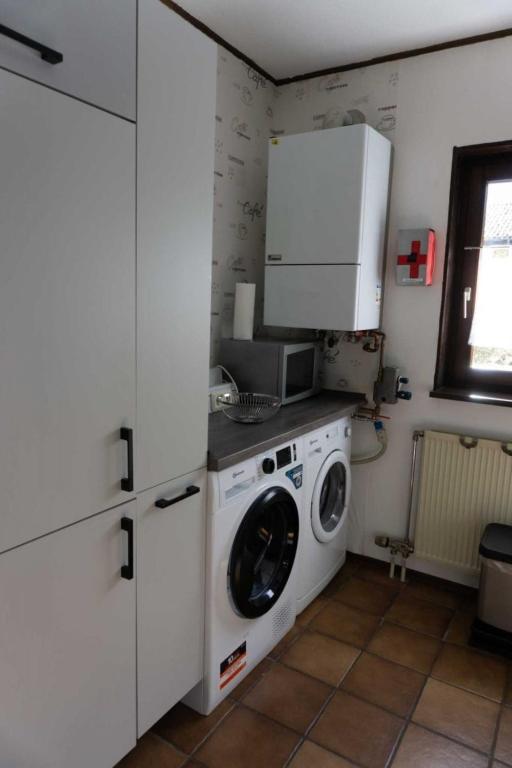 a kitchen with a washing machine and a microwave at Haus Im Wiesengrund OG in Thalfang