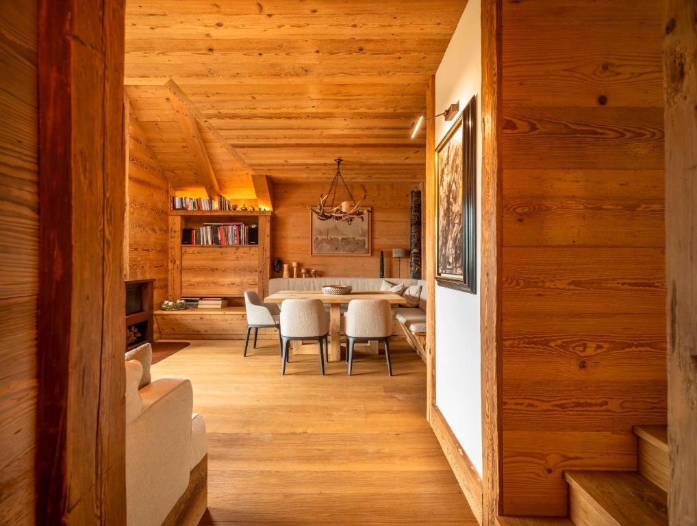 a dining room and kitchen with wooden walls and wood floors at Tablà del Bosco R&R in Cortina dʼAmpezzo