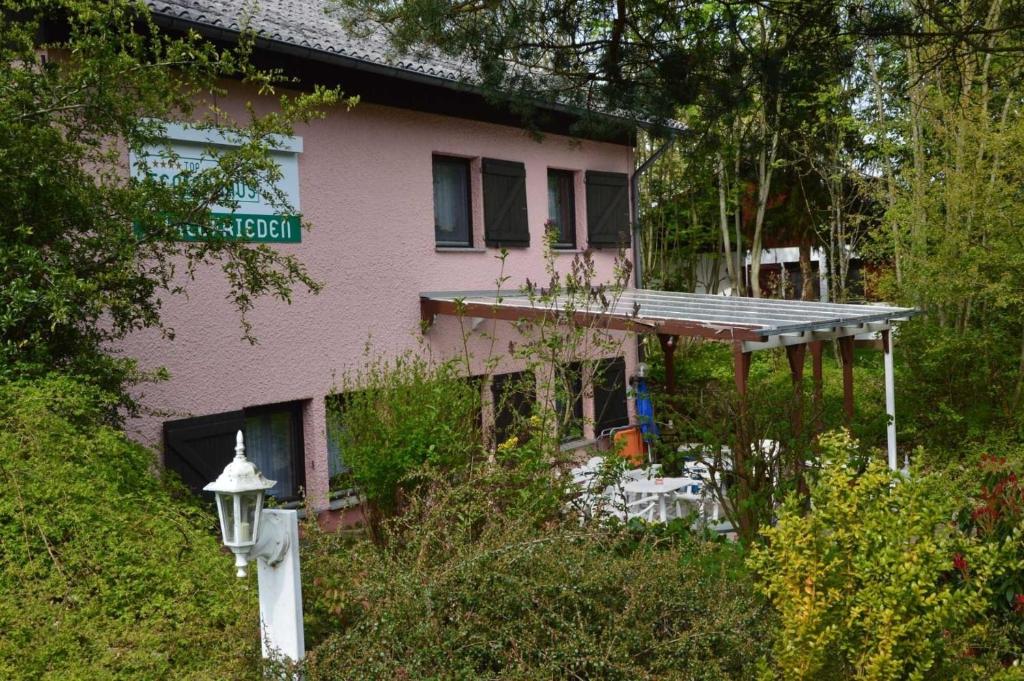 ThalfangにあるHaus Waldfrieden EGのポーチと道路標識のあるピンク色の家