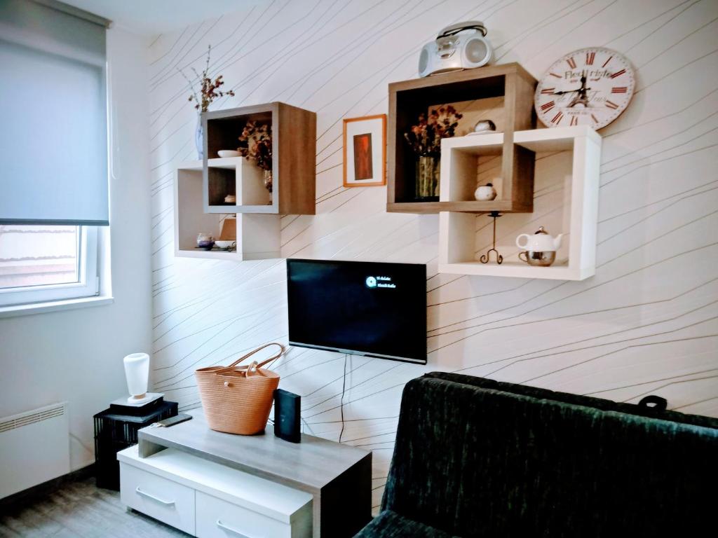 a living room with a couch and a clock on a wall at Studio SimpaKop in Kopaonik